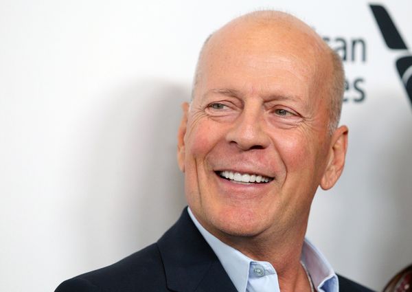 A white man in a suit smiles looking towards the left.