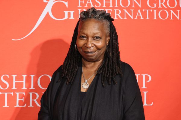 A Black woman wearing a black outfit smiles looking at the camera.