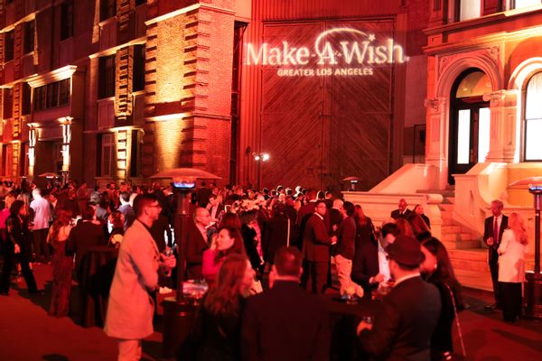 A building says Make-A-Wish Greater Los Angeles. A huge crowd of people stand outside the building.