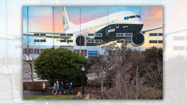 People walk on a path while a large image of a Boeing airplane can be seen behind them.