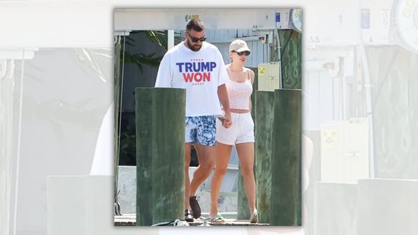 A white man and woman walk hand in hand. The man appears to be wearing a white shirt that says TRUMP WON.