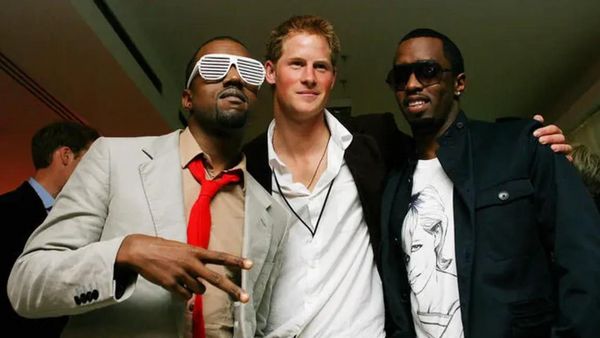 Two Black men stand on either side of a white man. The white man is wearing a suit jacket with a white shirt, while the Black man on the left is wearing white sunglasses and the Black man on the right is wearing a shirt that has a white woman pictured on it.
