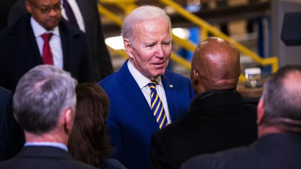 A white man talks to a Black man as a crowd of people surrounds them.