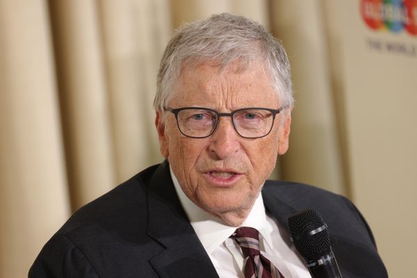 A white man wearing a black suit has his mouth slightly open.