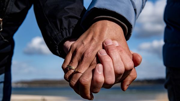 Two white people hold hands.