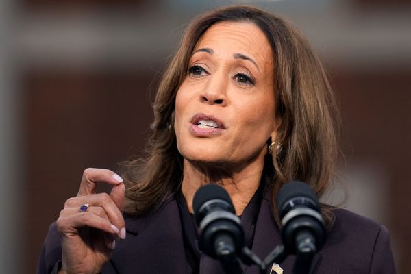 A Black South Asian woman standing at a podium wearing a dark suit.