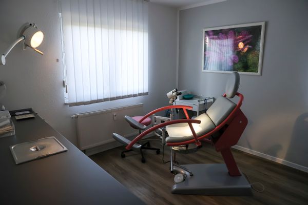 An empty gynecology chair with footholds sits in an office.