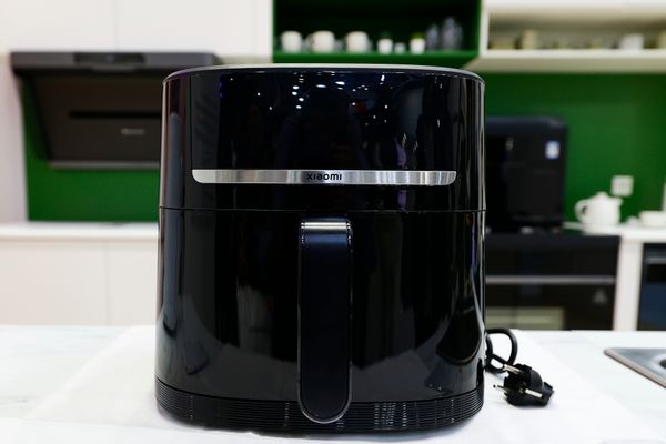A black air fryer is photographed sitting on what looks like a white counter.