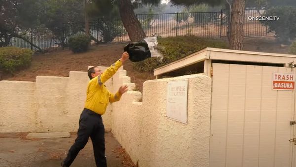 A person wearing a yellow top pours water over the top of a trash can.