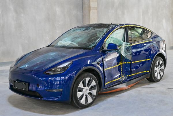 A blue car appears crashed, with it appearing heavily dented with windows shattered.