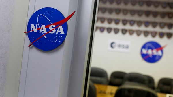 A doorway shows a blue sign with NASA in white on it. You can see seats in a room that has the same blue logo on it.