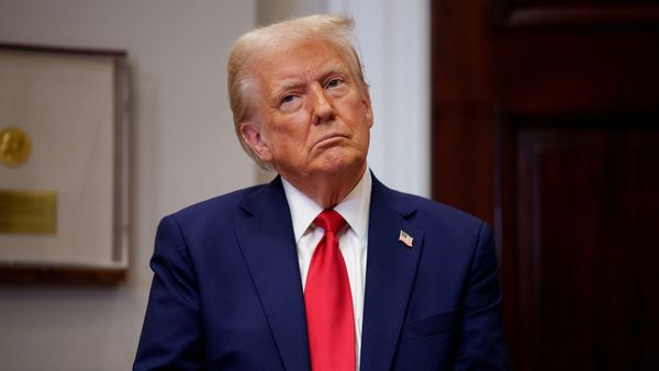 A white man wearing a blue suit looks forward.