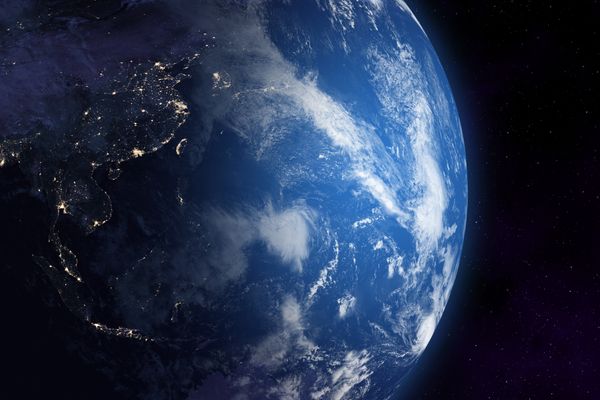 A blue planet is seen from space. Lights can be seen, indicating electricity/life there.