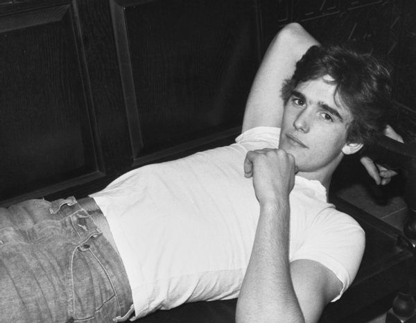 American actor Matt Dillon, wearing a white cap-sleeved t-shirt and jeans, reclining on a wooden seat, United States, circa 1983. (Photo by Vinnie Zuffante/Getty Images)