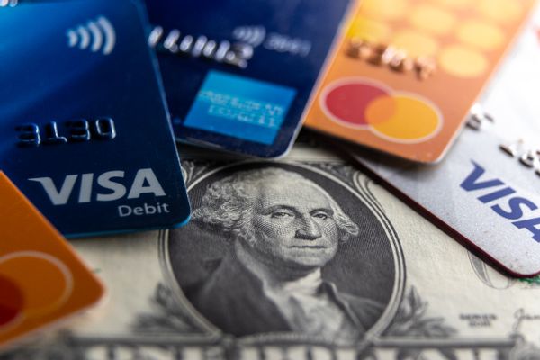 Five VISA credit cards are shown above $1 bills.
