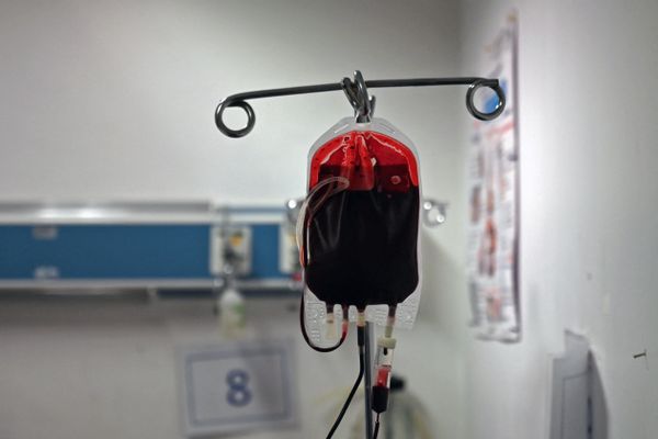 A bag of blood hangs in a hospital environment. 