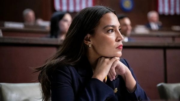 A Latina sitting down looks slightly to the right.