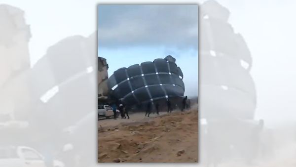 People surround what appears to be a large black balloon.