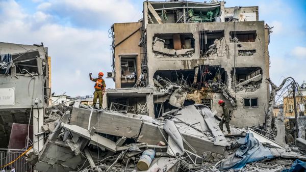 People stand on debris of buildings outside.