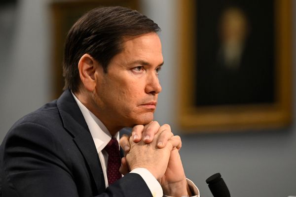 A Latino man with short black hair, Secretary of State Marco Rubio, holds his clasped hands up to his chin.