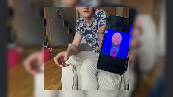 Person is shown holding a phone featuring bald JD vance meme
