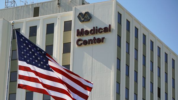 The exterior of the Tibor Rubin VA Medical Center in Long Beach, California. The building is multi-story, featuring large windows and a flat roof. A U.S. flag is visible in front of the entrance.