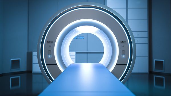 A modern MRI (Magnetic Resonance Imaging) machine in a clean, high-tech medical imaging room. The circular scanner is illuminated with blue and white lights, and a patient table extends into the center of the machine.