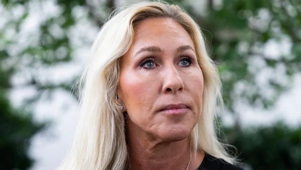 A white woman looks to the right while standing outside.