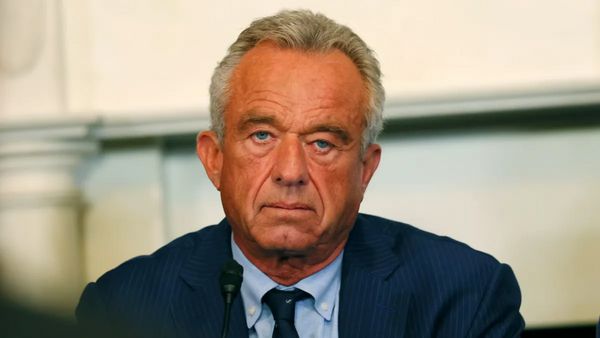 A white man wearing a blue suit looks at the camera.