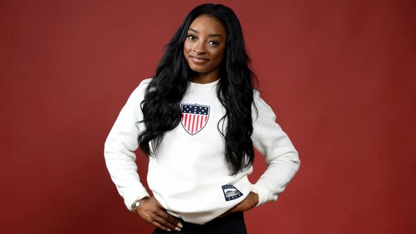 A Black woman wearing a white sweatshirt looks at the camera.