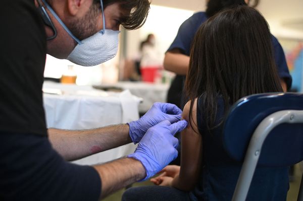 An adult places a bandaid on a child's arm. 