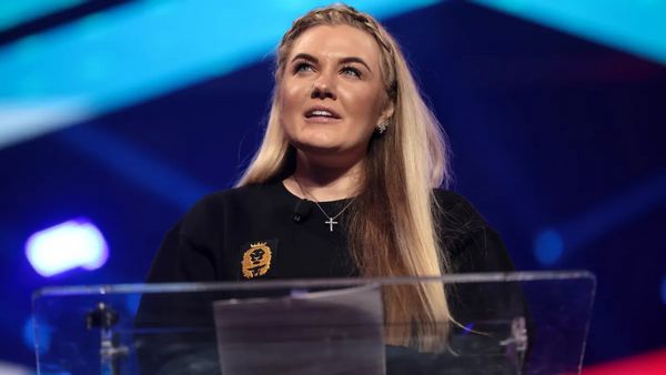 A white woman looks upwards while speaking at a podium.