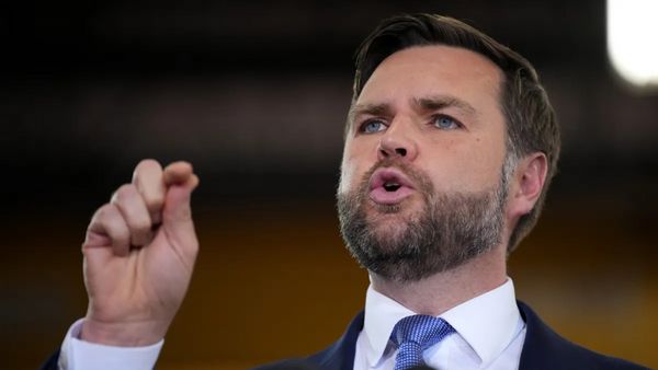 A white man wearing a black suit speaks.