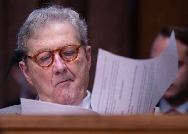 An older white man wearing circle glasses sifts through papers. 