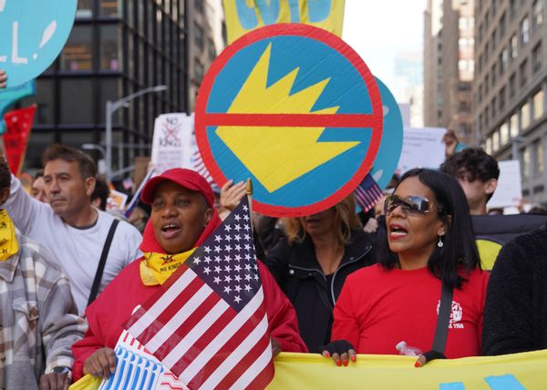 Protesters hold US flags and signs with a crown crossed out. 