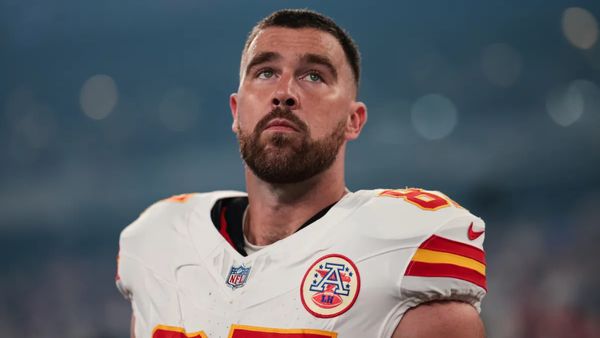 A white man wearing a white and red football uniform looks up.