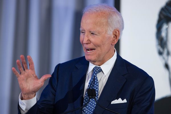 Former President Joe Biden holds up a hand while speaking.