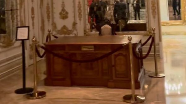 Blurry photo of a large wooden desk surrounded by ropes. 