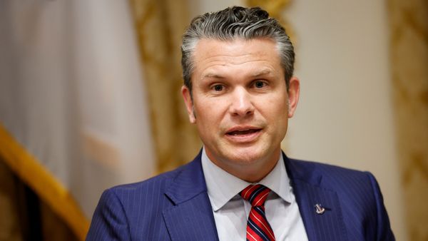 Pete Hegseth, a white man wearing a blue suit, appears to be speaking.