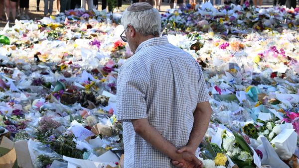 A man looks at a large amount of remembrances. He is facing away from the camera, with his arms around his back.
