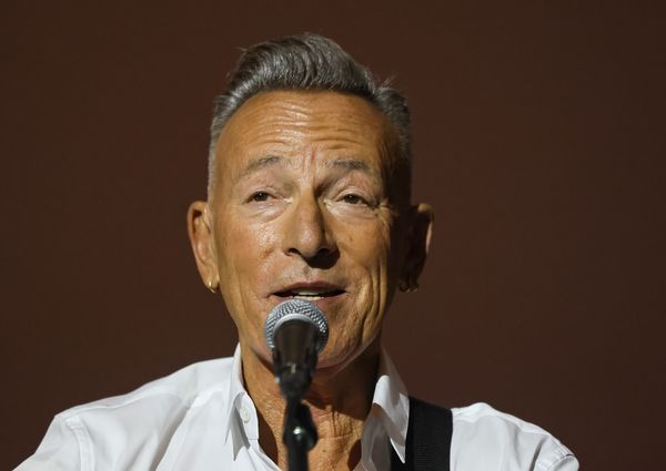Bruce Springsteen, who has short gray hair, sings into a microphone.