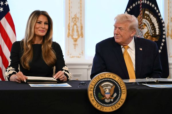 Melania Trump and U.S. President Donald Trump seated at a table, smiling. 