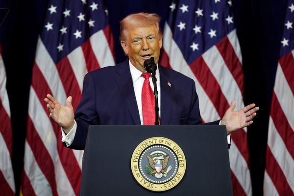 U.S. President Donald Trump stands at a podium and holds his hands up to his sides. 