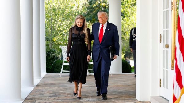 Turning Point USA CEO Erika Kirk, a white woman with blonde hair, wears a black dress and shoes and walks next to U.S. President Donald Trump.