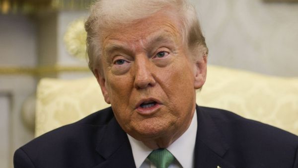 A white man wearing a black suit speaks.