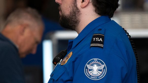 A white TSA agent in a blue shirt monitors passengers at Minneapolis-St. Paul International Airport Terminal 1 on March 23, 2026, in Minneapolis, Minnesota.