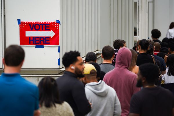 People wait in line next to a "vote here" sign.