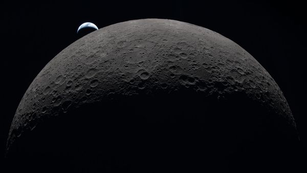 High definition image of the moon and its craters with a blue Earth visible in the background, partially obscured by shadow. 