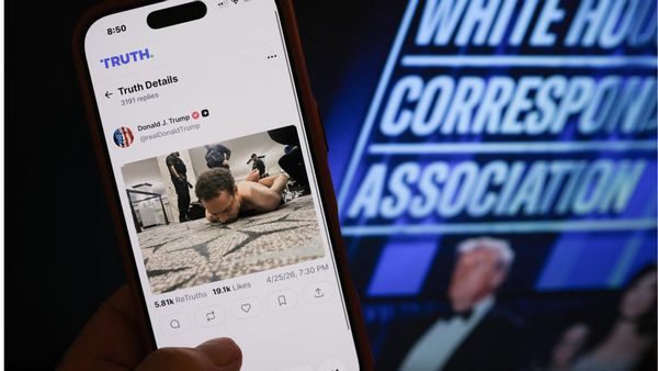 Image shows phone with a Truth Social post against a background of a scene from the White House Correspondents' Association dinner