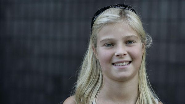 Tilly Smith, a young girl with blonde hair, blue eyes, and black sunglasses on top of her head, smiles while looking at the camera.